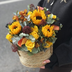 Композиция в сумке "Тональность" из подсолнухов, калл, ягод вибирнума, лимонных роз, скиммии и орхидеи в Долгопрудном